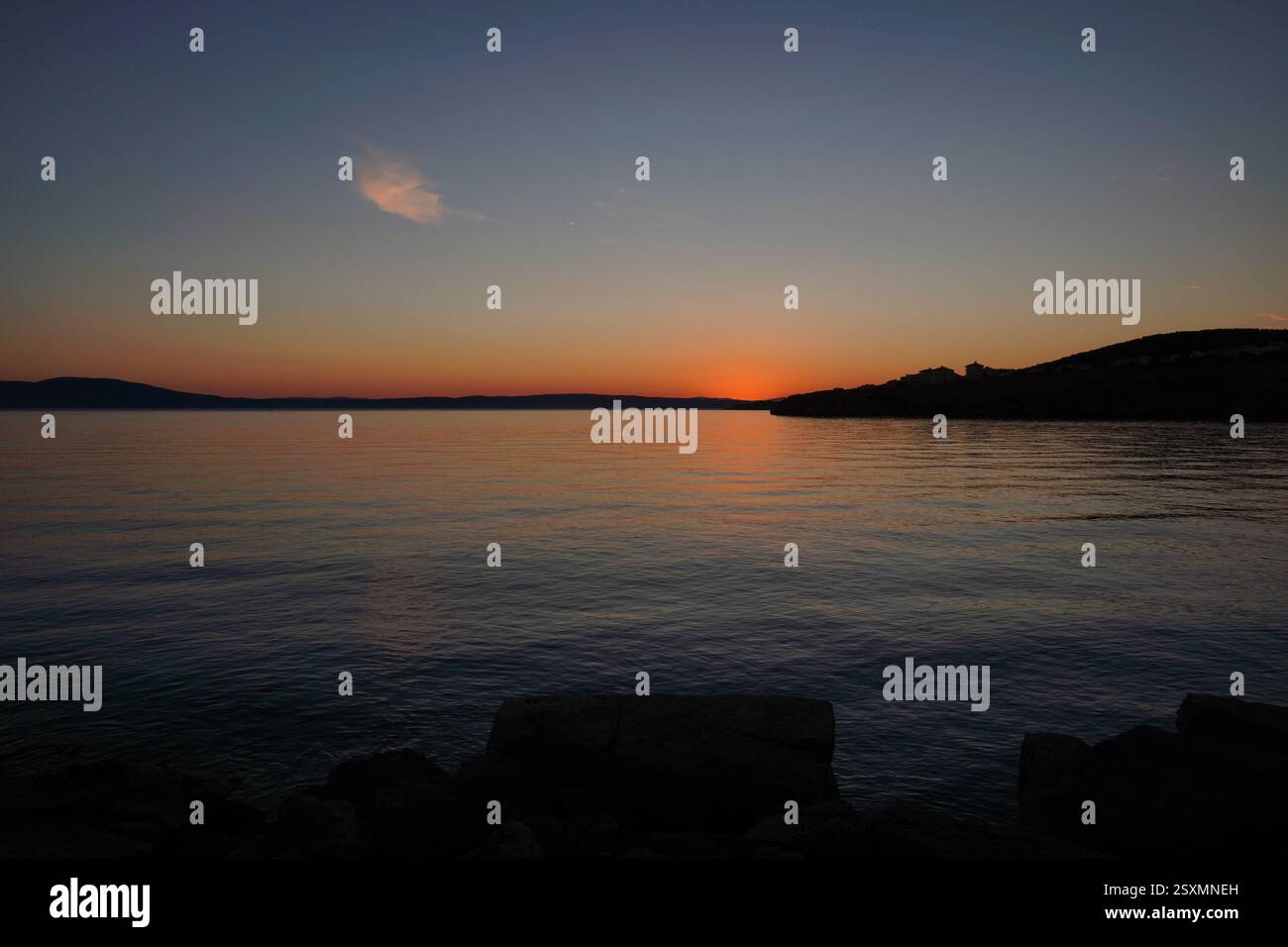 Sonnenuntergang in der Nähe des Meeres, keine Wolken. Farbenfroher Himmel und Spiegel im Wasser. Kleine Wellen im Ozean. Erholung im Urlaub, Ruhe und Entspannung, Hintergrundbild Stockfoto