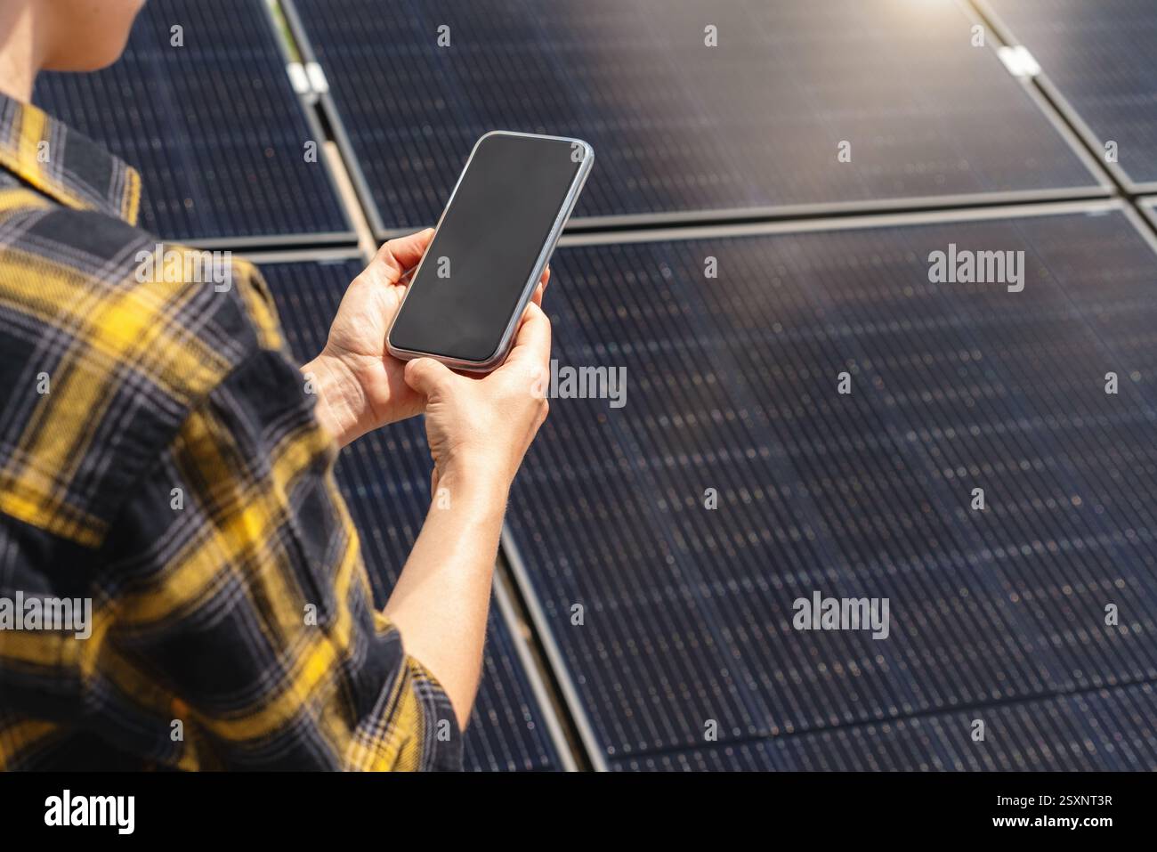 Weibliche Ingenieurin im Solarkraftwerk, die drahtlose Technologie zur Überwachung von Panels verwendet Stockfoto