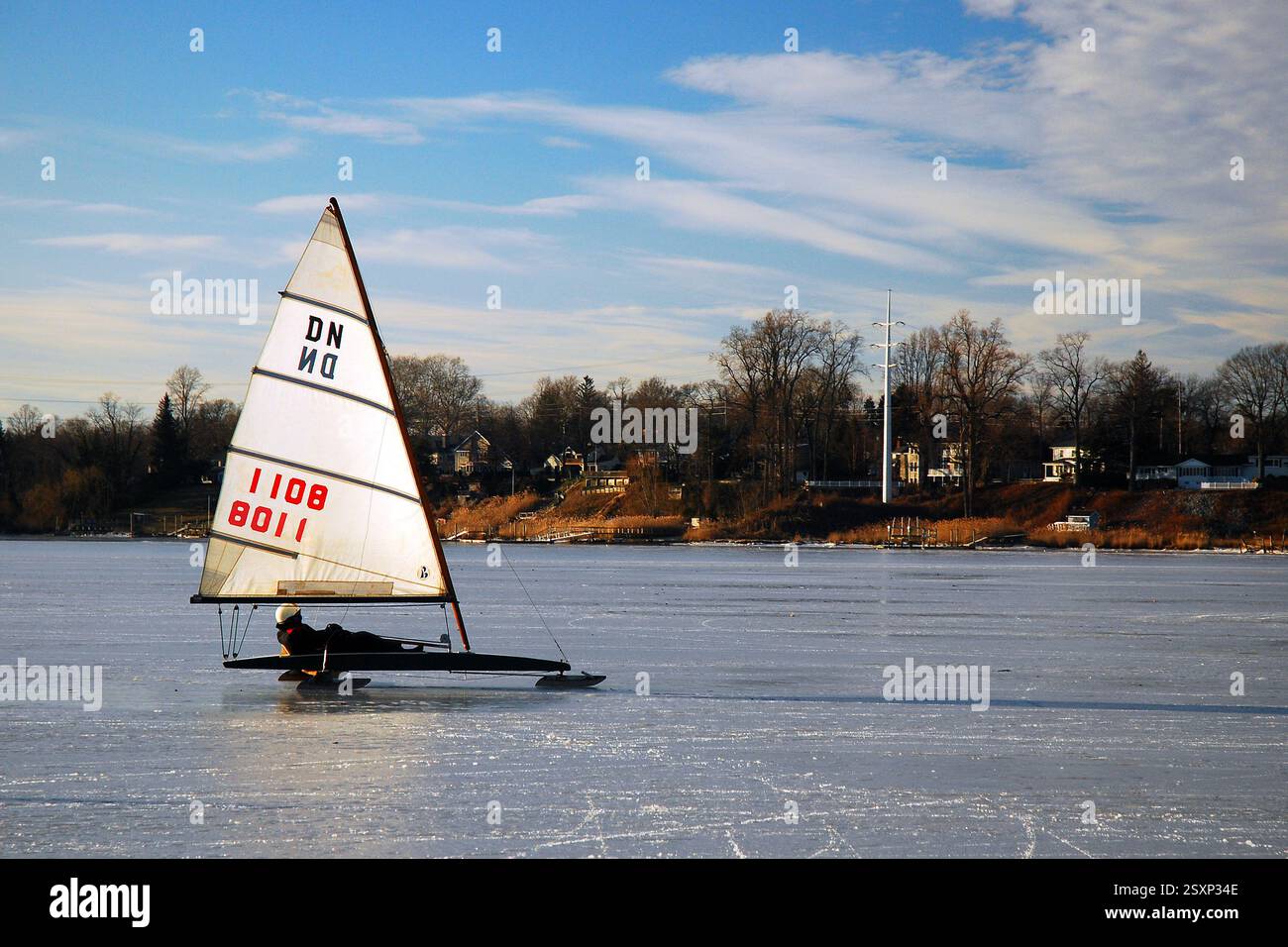 Ein erwachsener Mann gleitet auf seiner Eisyacht über einen gefrorenen Fluss Stockfoto