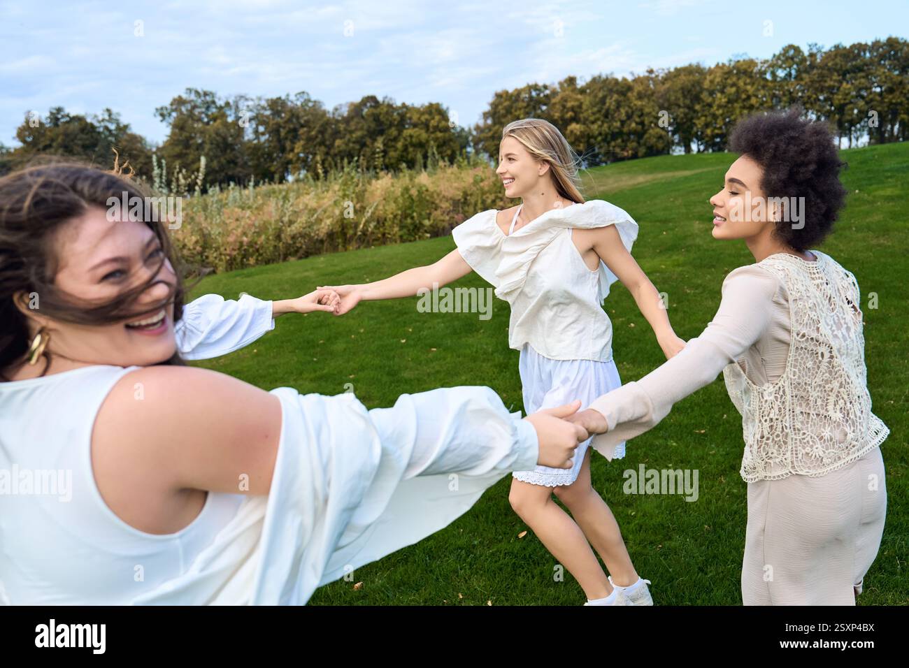 Drei stilvolle Freunde teilen sich einen verspielten Moment in einem lebhaften Frühlingspark. Stockfoto
