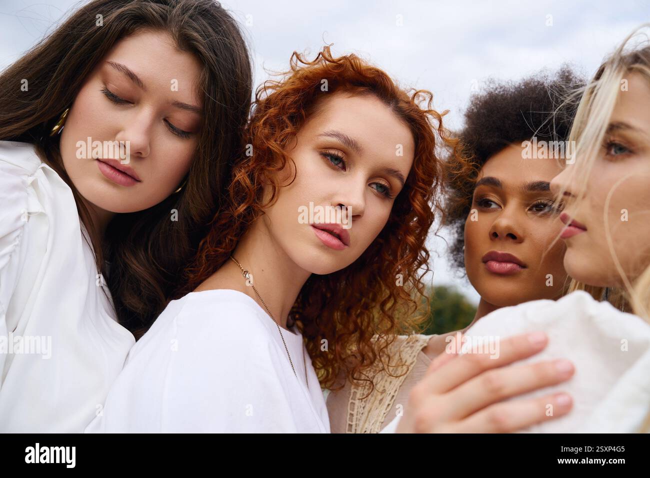Vier selbstbewusste Frauen genießen die Schönheit des Frühlings und präsentieren ihre modischen Styles in der Natur. Stockfoto