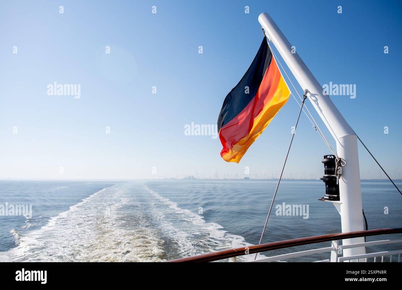 Borkum, Deutschland. Juni 2024. Eine Flagge der Bundesrepublik Deutschland fliegt auf einer Fähre der AG Ems während der Überfahrt zur Insel Borkum. Die Reederei betreibt den Fährdienst von Emden und dem niederländischen Hafen Eemshaven zur westlichsten Nordseeinsel Deutschlands. Quelle: Hauke-Christian Dittrich/dpa/Alamy Live News Stockfoto