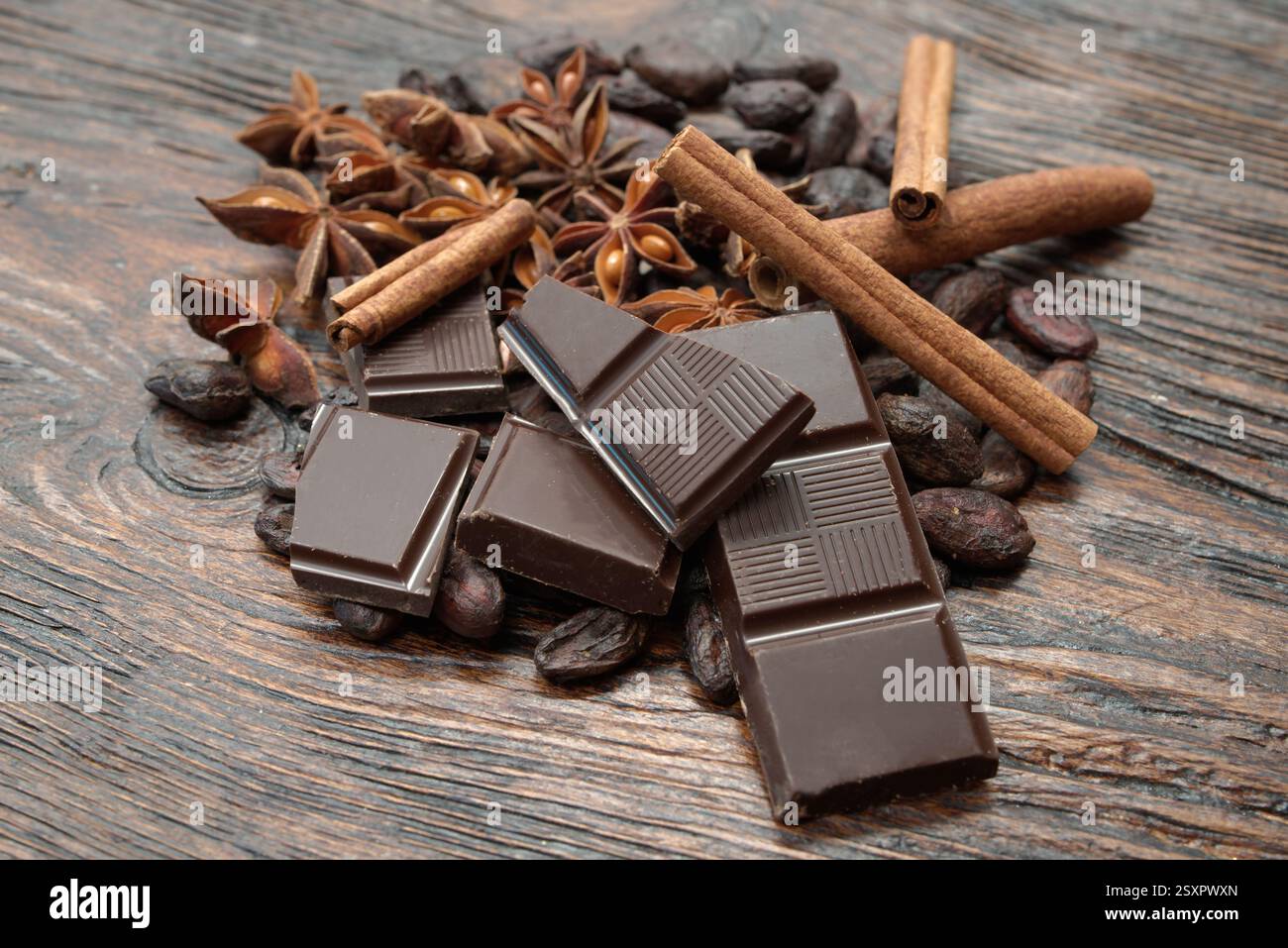 Zerbrochene dunkle Schokolade und Kakaobohnen auf dem Tisch Stockfoto