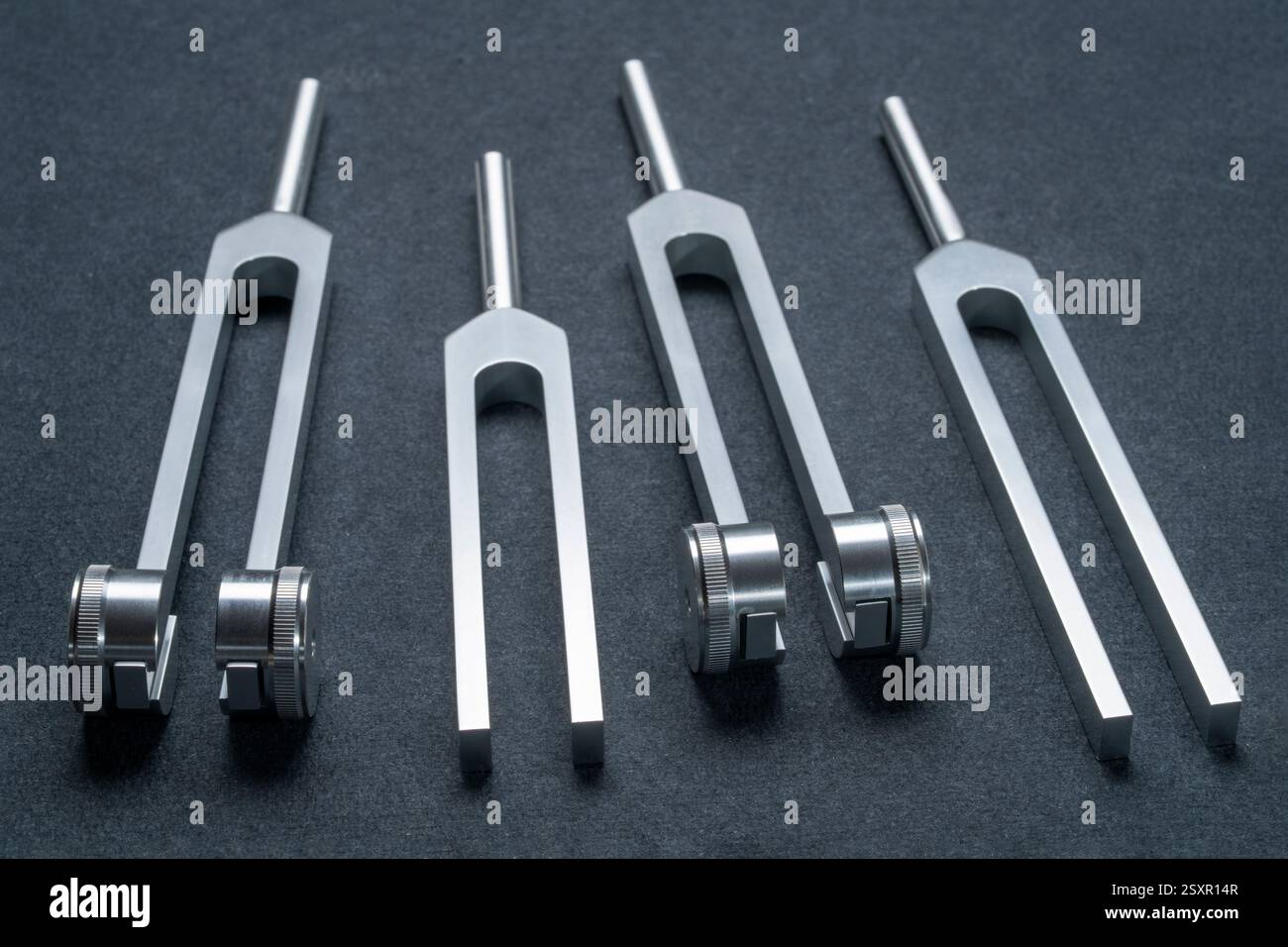 Satz gewichteter und ungewichteter Stimmgabeln aus Metall, die zum Abstimmen von Musikinstrumenten, zur Klangtherapie, zur Chakra-Heilung oder Entspannung verwendet werden. Stockfoto