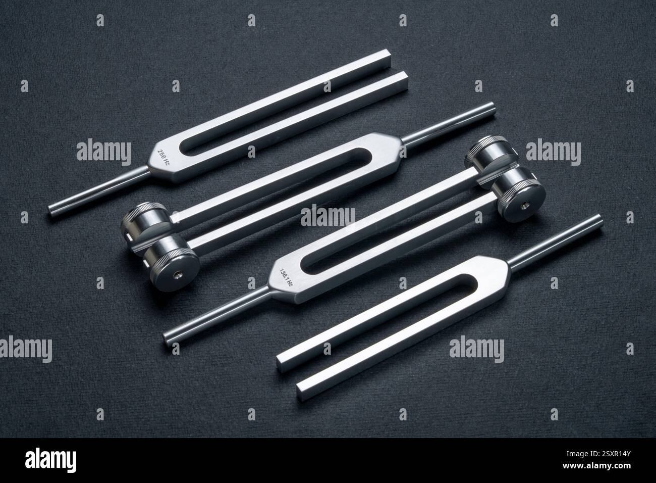 Satz gewichteter und ungewichteter Stimmgabeln aus Metall, die zum Abstimmen von Musikinstrumenten, zur Klangtherapie, zur Chakra-Heilung oder Entspannung verwendet werden. Stockfoto