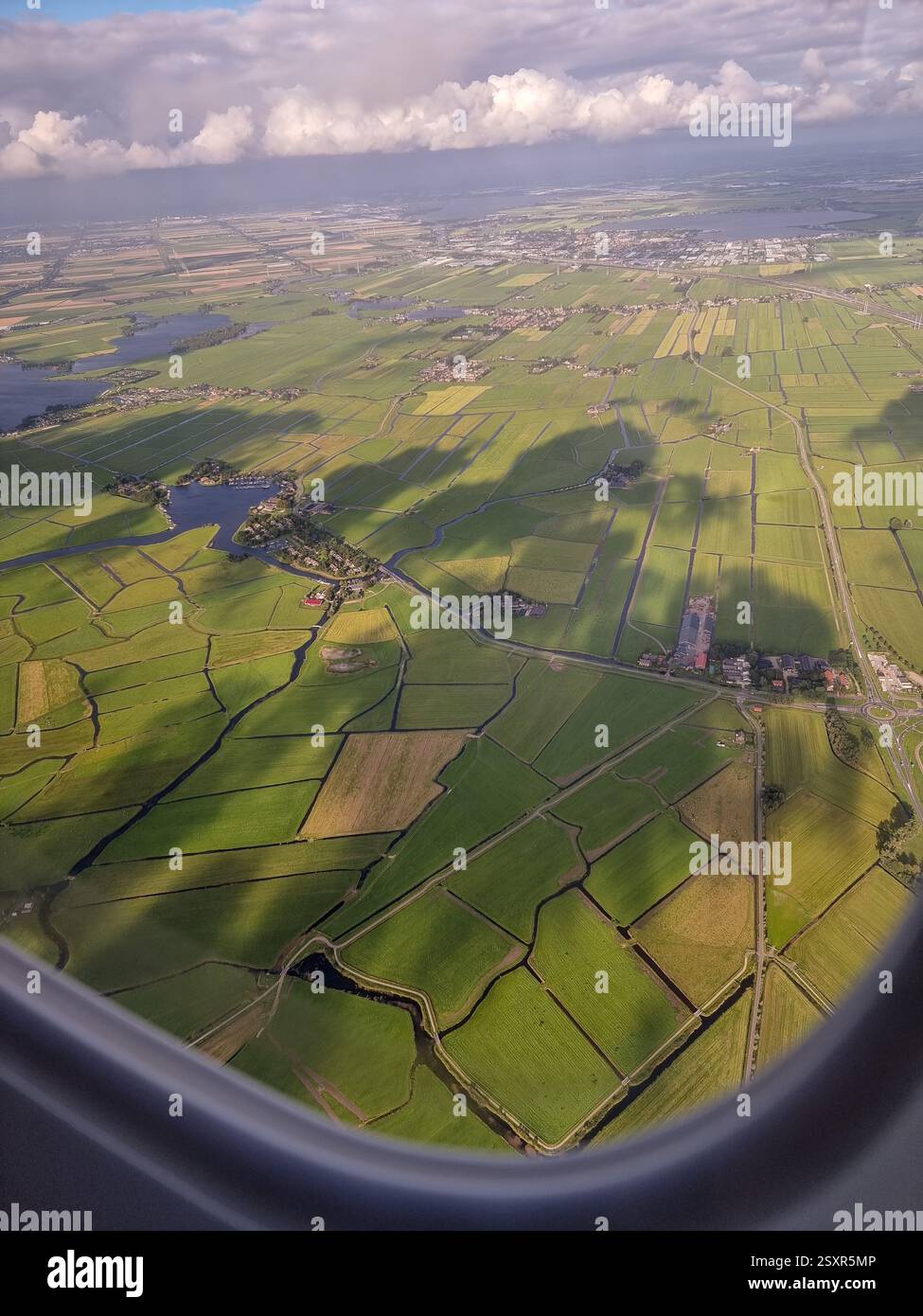 Luftaufnahme von einem Flugzeugfenster auf grüne typisch niederländische Landschaft (Niederlande) unter Meeresspiegel: Polder; an einem sonnigen Tag - Smartphone-aufgenommenes Stockfoto
