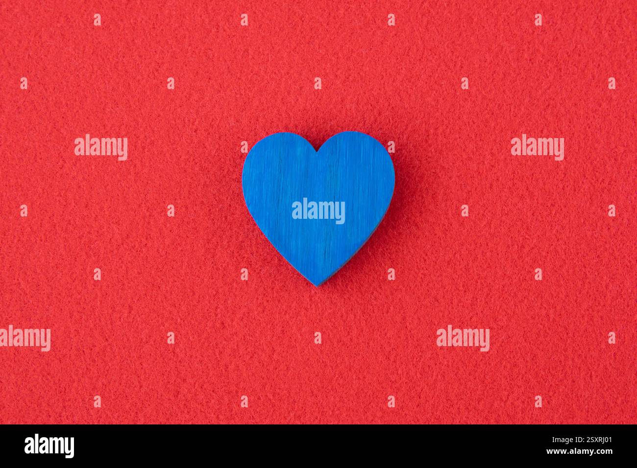 Blaues Holzherz auf rotem Stoffhintergrund mit Platz für Text. Konzept für Karte. Stockfoto