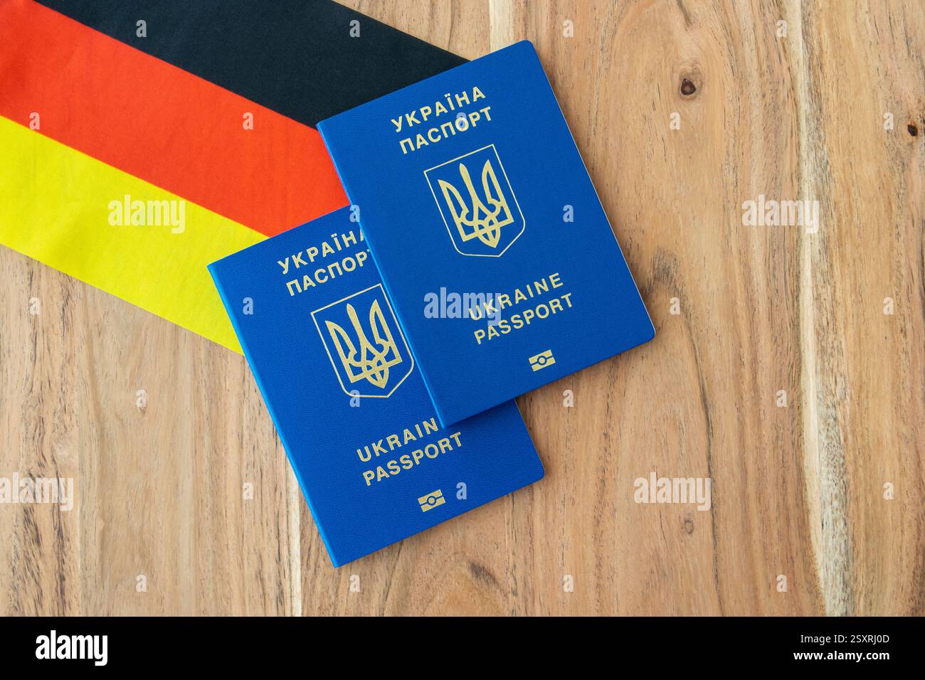 Ukrainischer Pass auf dem Hintergrund der deutschen Flagge. Reise, Geschäftsreise oder Auswanderung. Stockfoto Ukrainischer Pass auf dem Hintergrund der deutschen Flagge. Reise, Geschäftsreise oder Auswanderung. Stockfoto