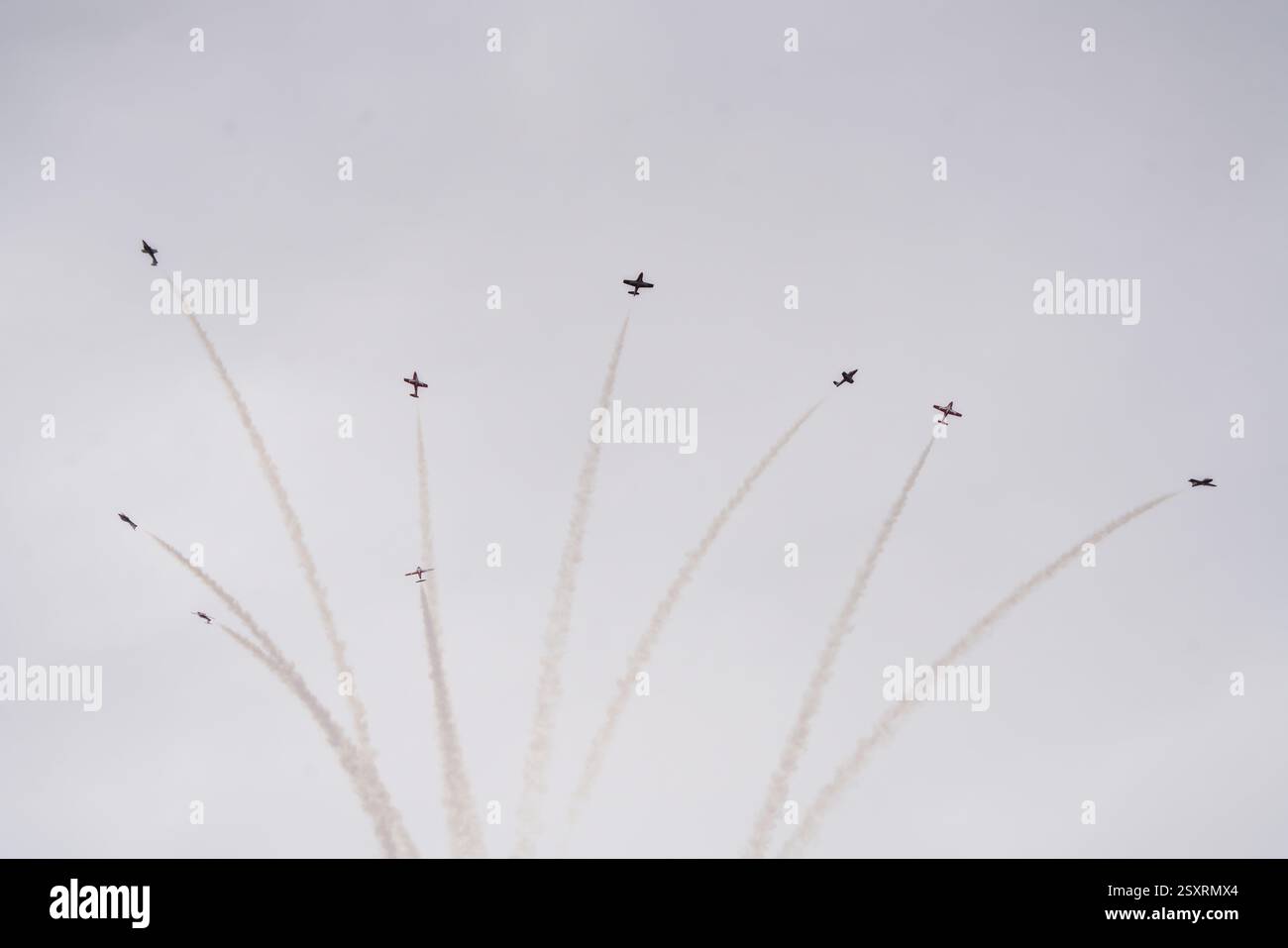Kleine Kunstflugzeuge, die während einer Flugschau Stunts durchführen und weiße Pfade am Himmel zeichnen Stockfoto