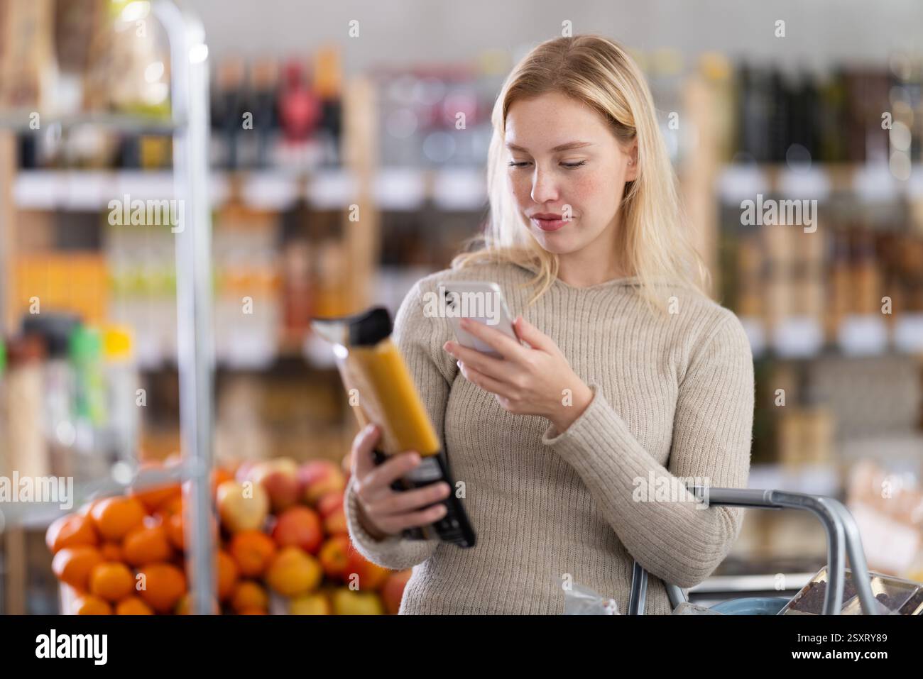 Prüfen des Ablaufdatums von Spaghetti – weibliche Käuferinnen scannen den QR-Code auf dem Etikett von Spaghetti mit Smartphone Stockfoto