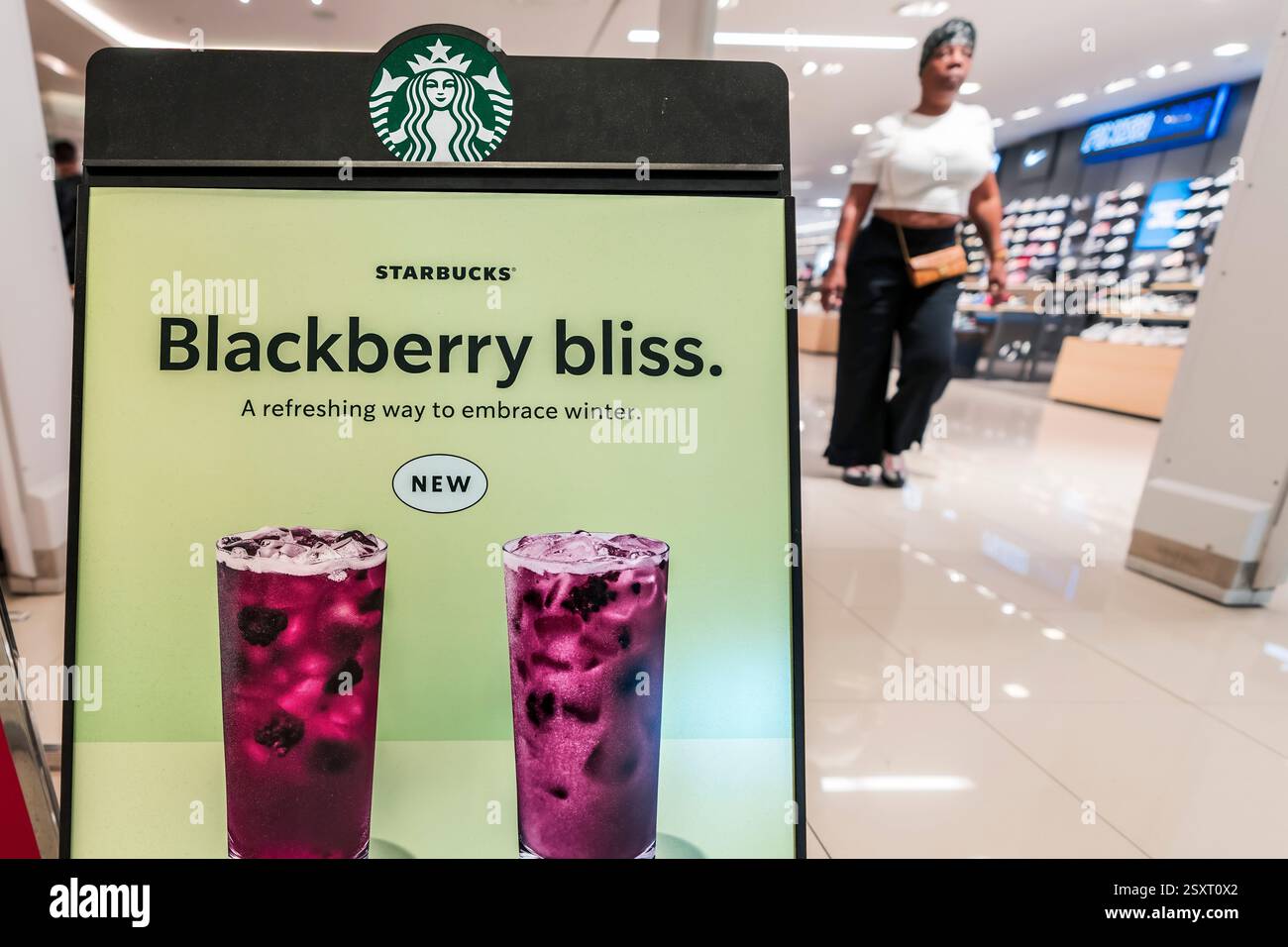 Miami, USA. Februar 2025. Am 25. Februar 2025 läuft eine Frau an Starbucks Signage in einem der Coffee Shops des Unternehmens in Aventura, Florida vorbei. Starbucks hat 1.100 Arbeiter entlassen und schrumpft die Getränkekarte. Foto: Ronen Tivony/SIPA USA) *** Bitte verwenden Sie das Guthaben aus dem Kreditfeld *** Guthaben: SIPA USA/Alamy Live News Stockfoto