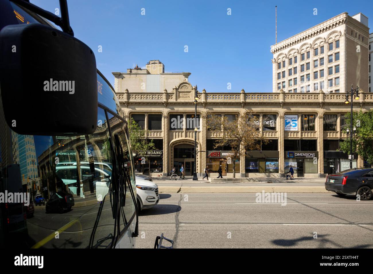 Das 1915 erbaute Curry-Gebäude und ein Bus entlang der Portage Avenue in Winnipeg, Manitoba, Kanada Stockfoto