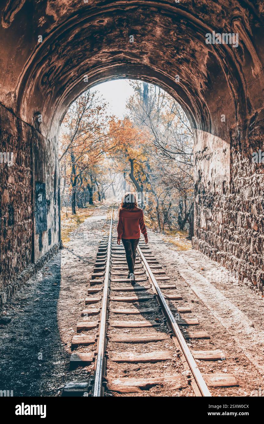 Mädchen im Wald. Das Mädchen läuft mit der Eisenbahn im Wald. Feenwald und Mädchen. Das Mädchen läuft mit der Bahn durch den Tunnel Stockfoto