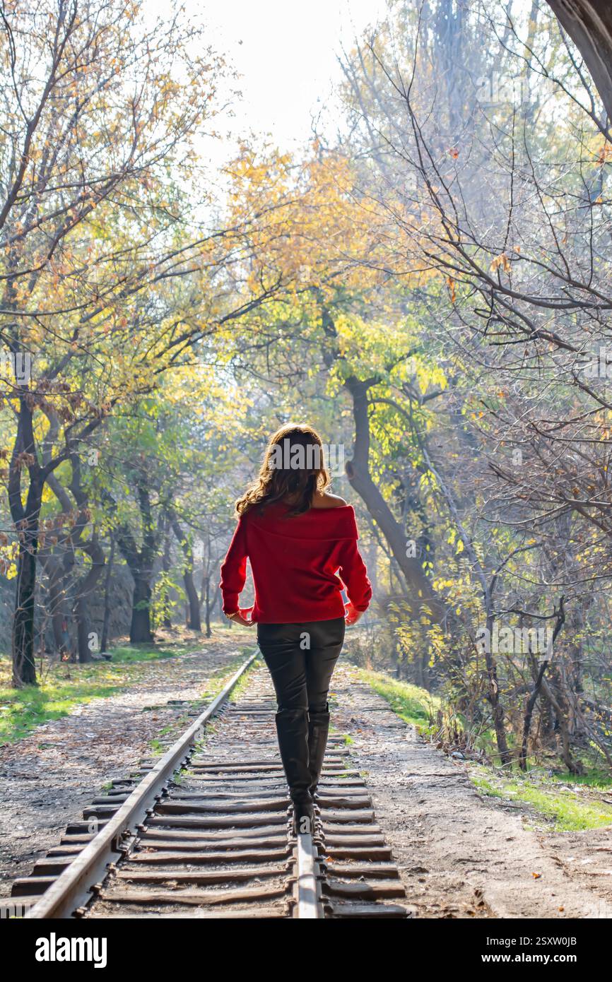 Mädchen im Wald. Das Mädchen läuft mit der Eisenbahn im Wald. Feenwald und Mädchen. Das Mädchen läuft mit der Bahn durch den Tunnel Stockfoto