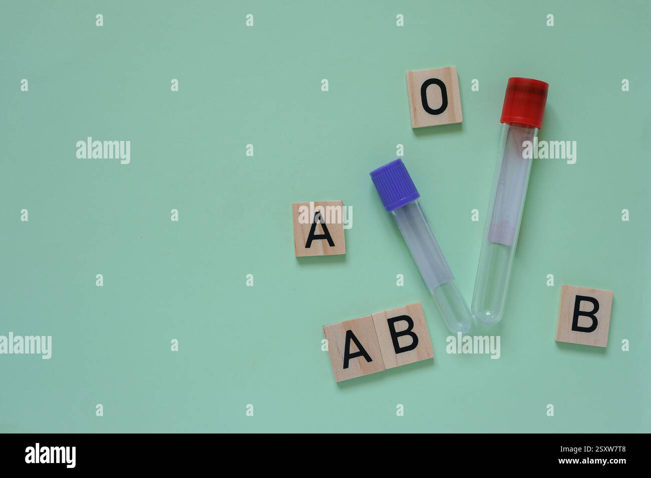 Reagenzgläser mit roten und violetten Stopfen. Holzwürfel mit Buchstaben repräsentieren verschiedene Blutgruppen mittlere aquamarinfarbene Hintergründe. Kopierbereich. Stockfoto