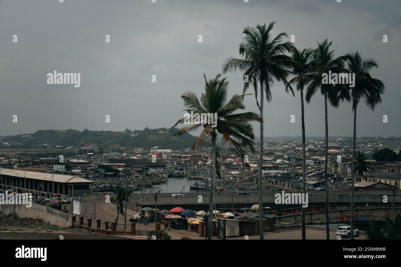Das Panorama von Elmina, Stadt in Ghana, Westafrika, mit den Fischerbooten auf dem Wasser, Palmen und armen Vierteln. Stockfoto