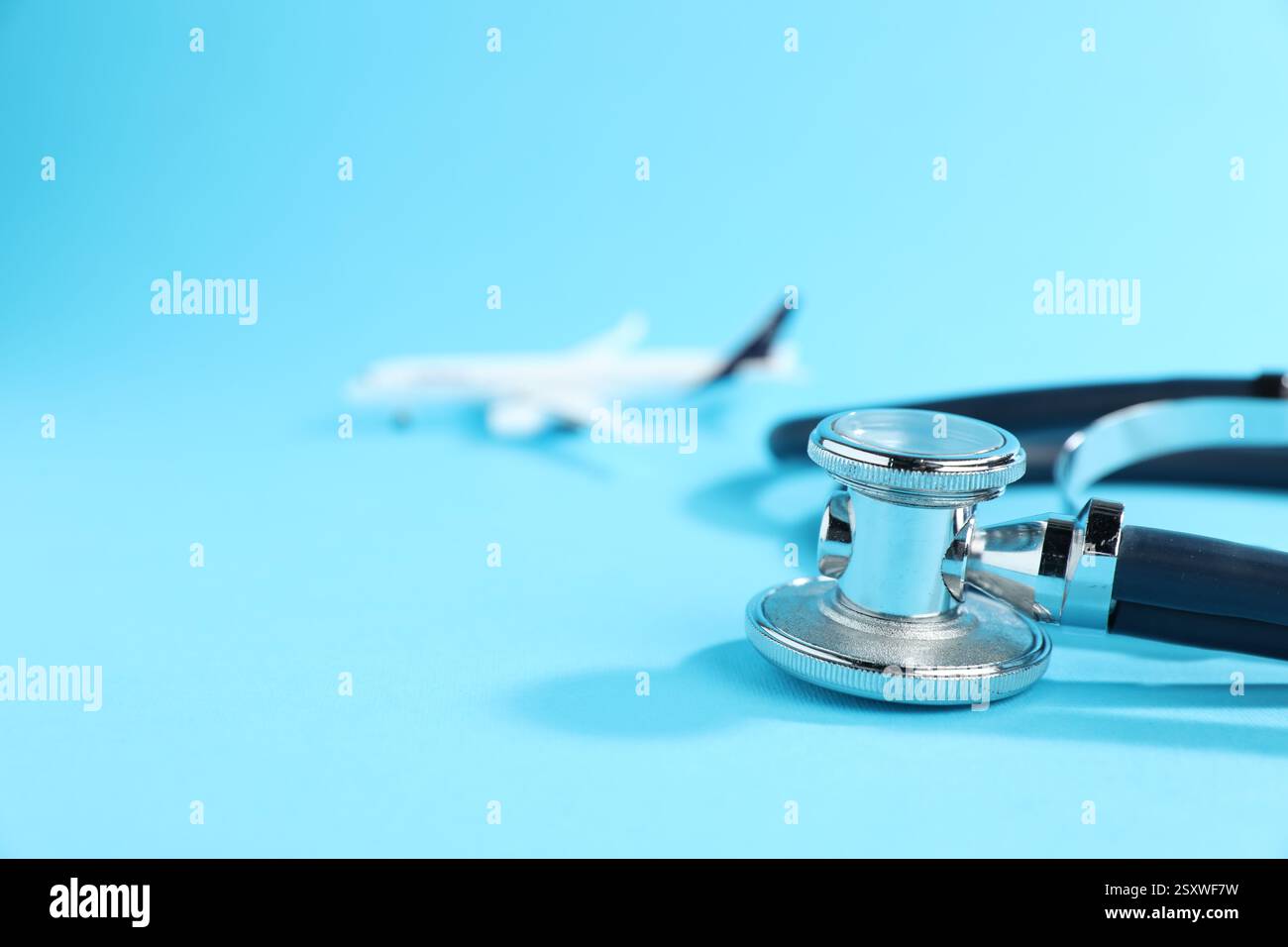 Stethoskop und Flugzeugmodell auf hellblauem Hintergrund, selektiver Fokus. Leerzeichen für Text Stockfoto