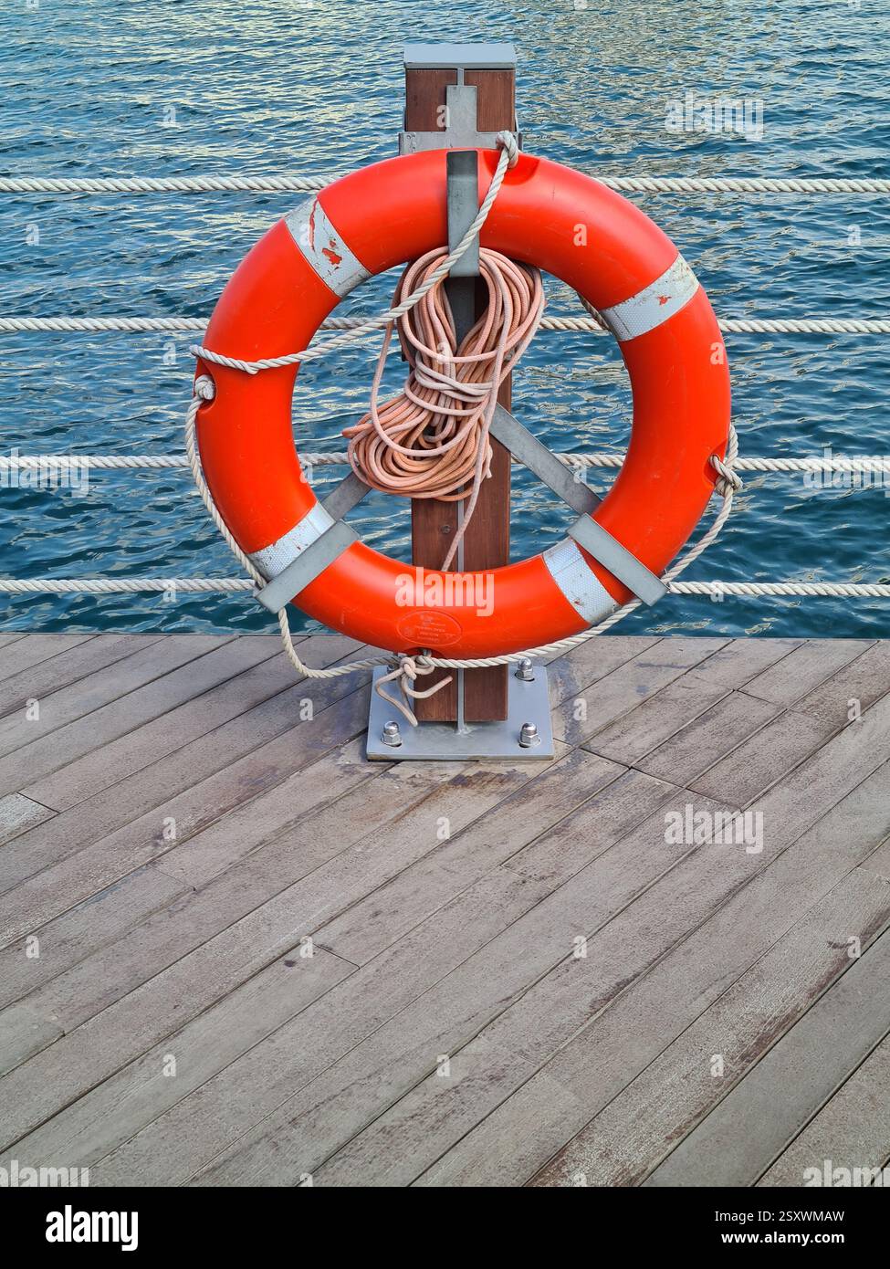 Portrait Nahaufnahme einer Red Life Boje auf einem hölzernen Deck vor dem Calm Water in Dubai - Smartphone-aufgenommenes Stockfoto