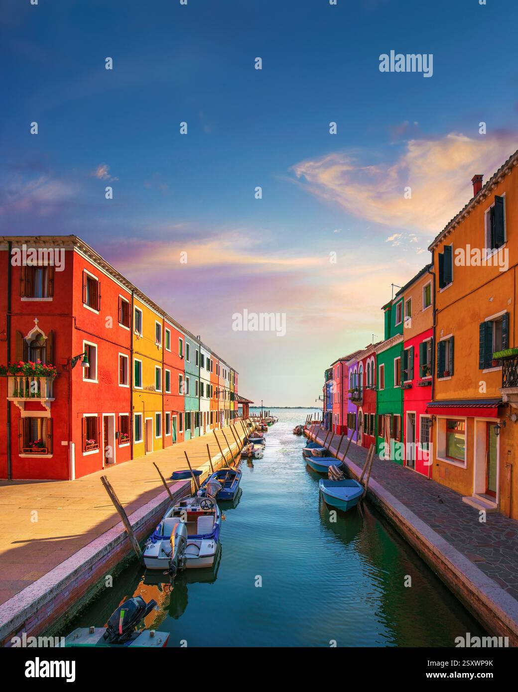 Burano Island Canal und Boote mit farbenfrohen Häusern bei Sonnenuntergang. Lagune von Venedig, Region Venetien, Italien. Hochformat und Kopierraum am Himmel – perfekt Stockfoto
