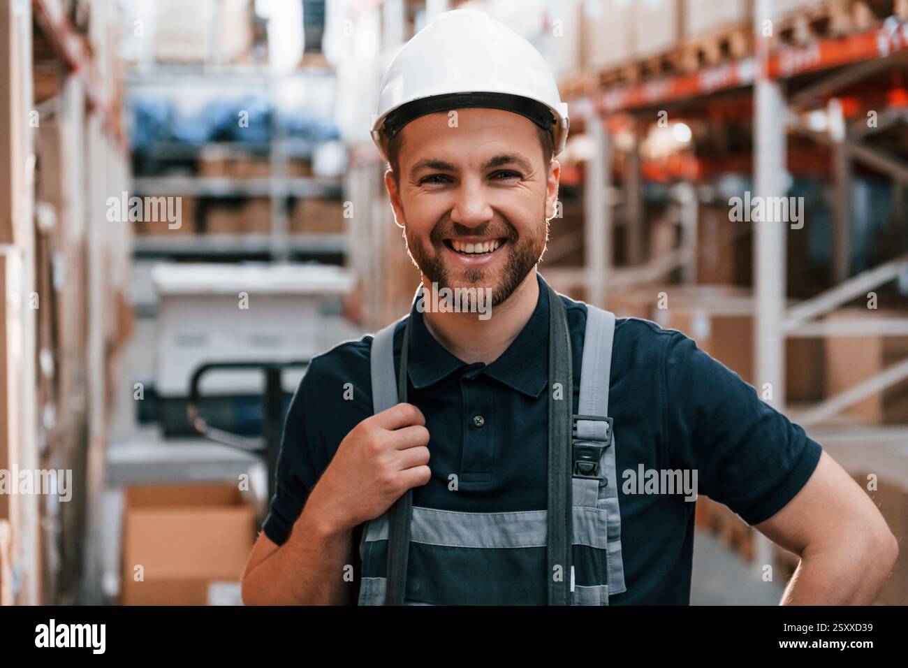 Lächelnd für die Kamera. Mitarbeiter in Uniform arbeitet tagsüber im Lager. Stockfoto
