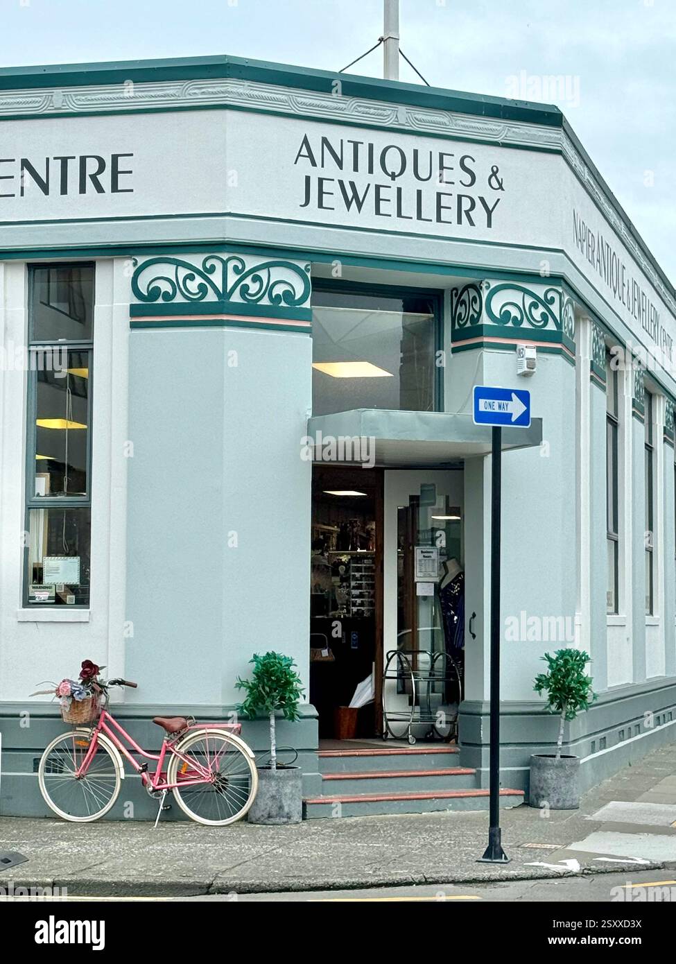 Pinkfarbenes Fahrrad vor dem Napier Antiques and Jewellery Centre in einem architektonischen Gebäude im Art déco-Stil in Napier Neuseeland - Smartphone-aufgenommenes Stockfoto