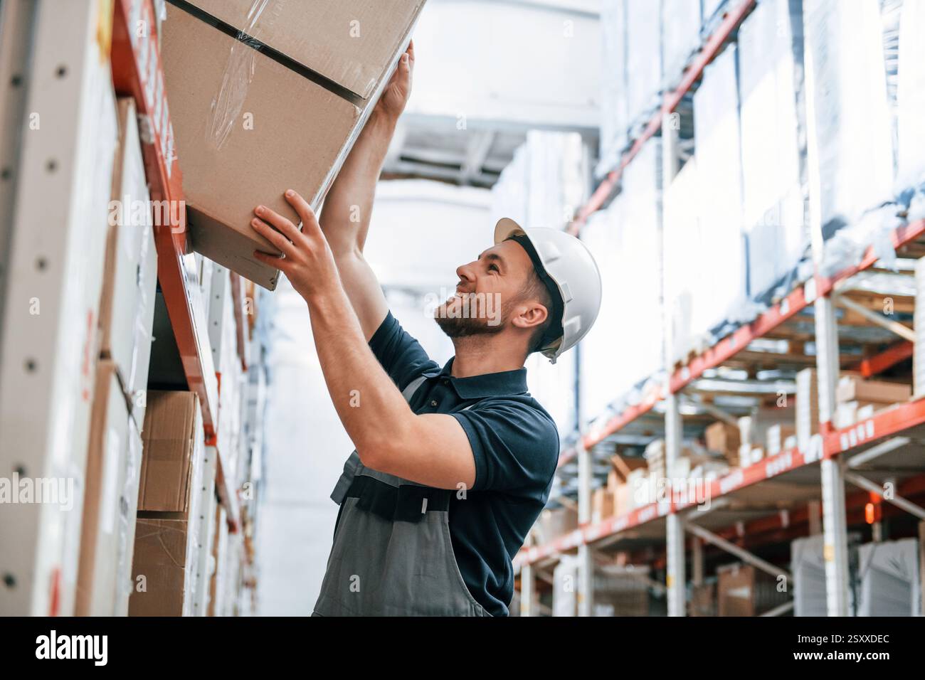 Nehmen Sie die Box heraus. Mitarbeiter in Uniform arbeitet tagsüber im Lager. Stockfoto