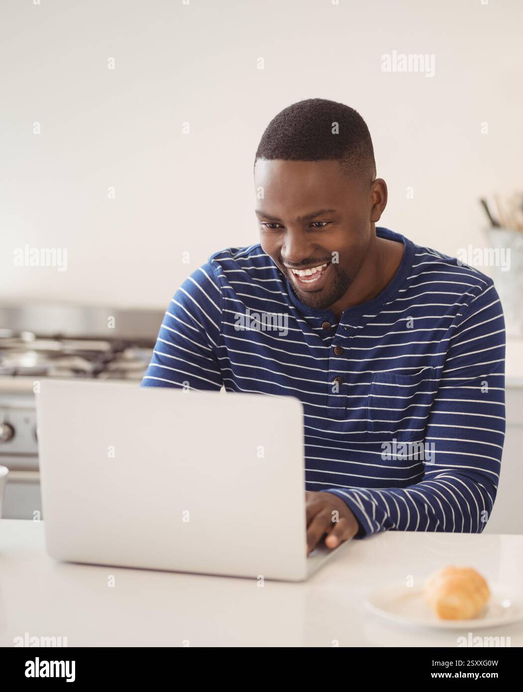 Lächelnder Mann, der zu Hause ein Notebook benutzt und produktive Arbeitssitzungen genießt Stockfoto
