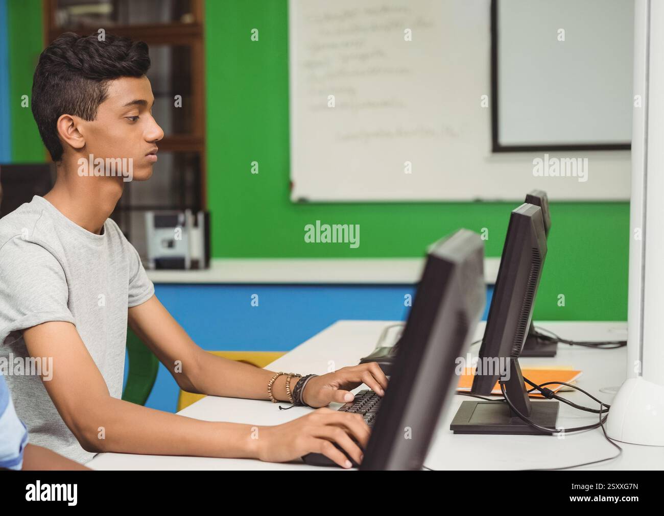 Der Schüler tippt am Computer im Klassenzimmer und konzentriert sich auf die Aufgabe Stockfoto