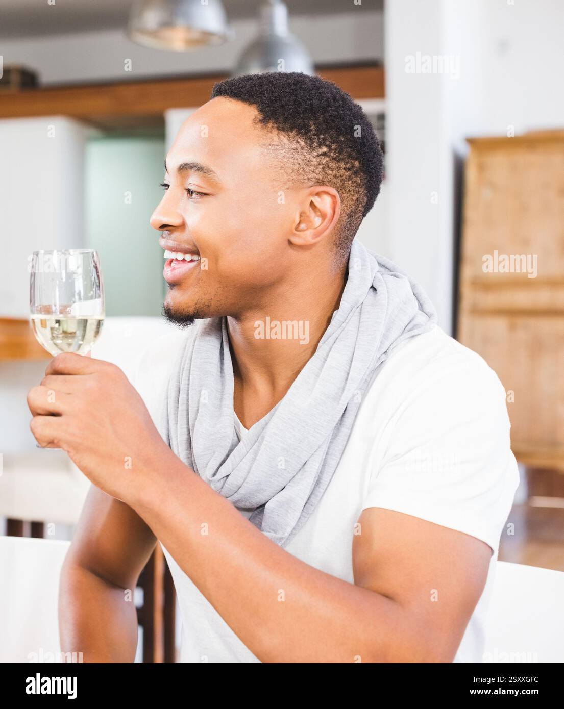 Ein lächelnder Mann genießt ein Glas Wein zu Hause, fühlt sich entspannt und glücklich Stockfoto