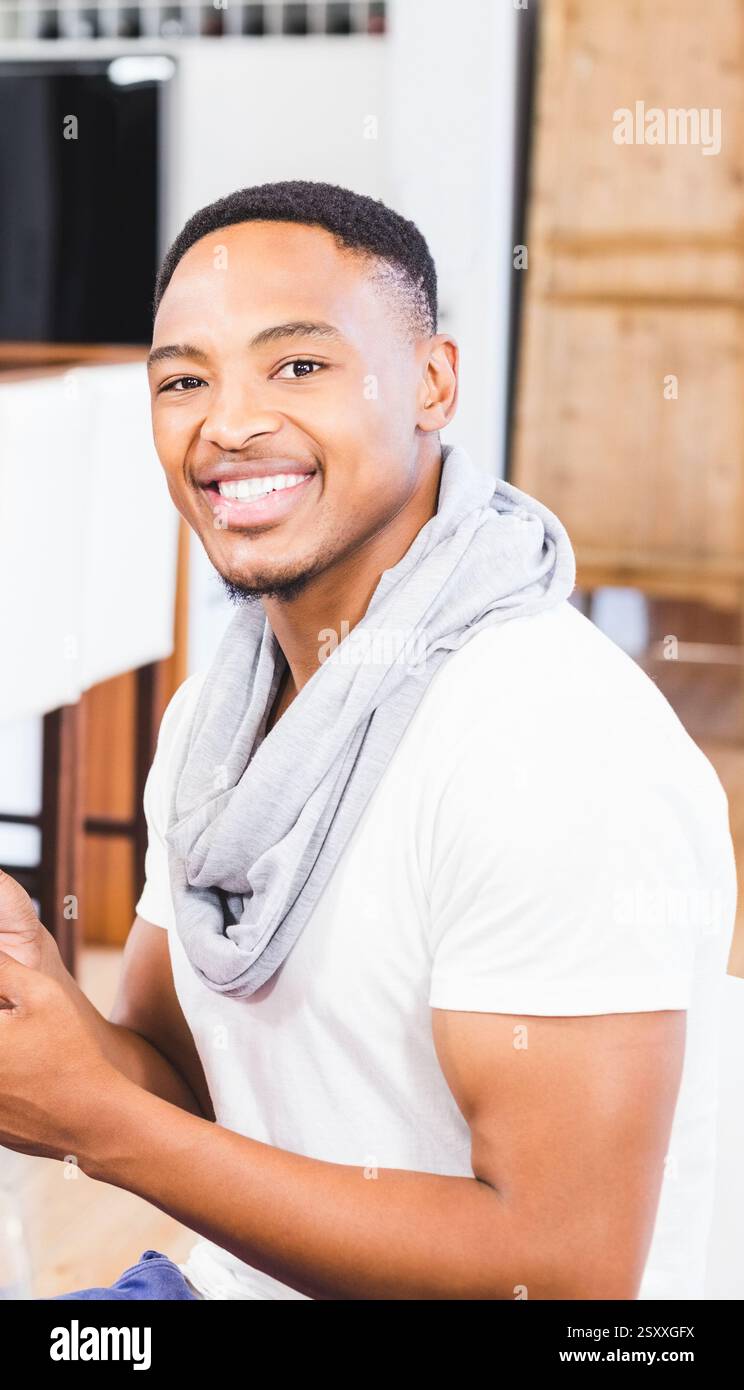 Ein lächelnder Afroamerikaner genießt die Zeit zu Hause und trägt ein lässiges weißes Hemd Stockfoto