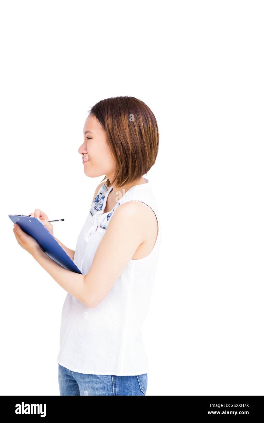 Ich halte das Klemmbrett, die Frau schreibt Notizen in lässiger Kleidung, lächelt selbstbewusst Stockfoto