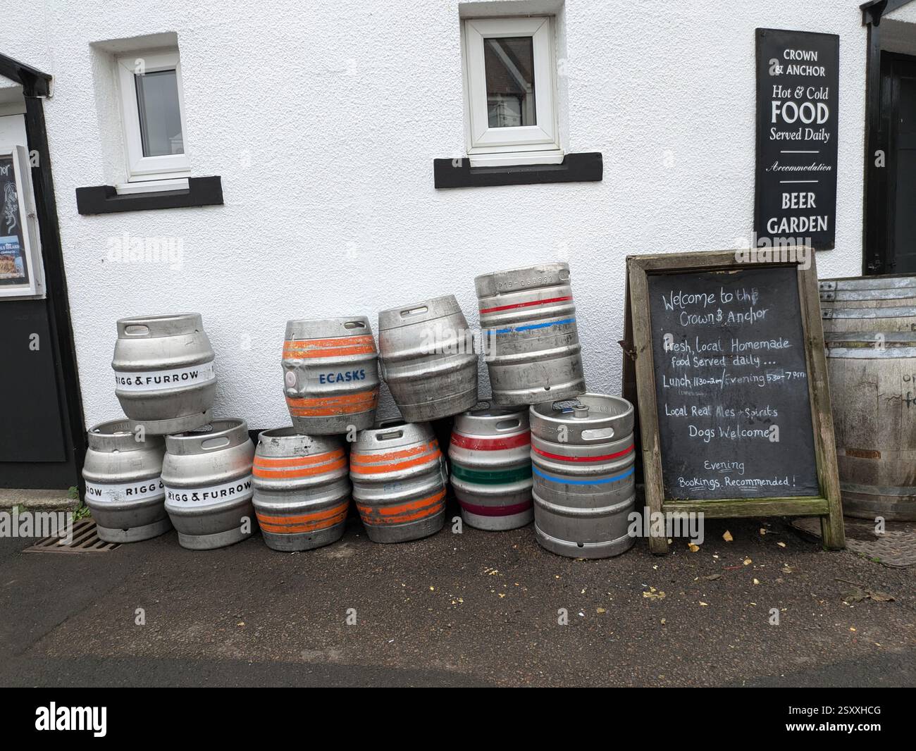 Bierfässer (Fässer) stapeln sich an der Wand eines Pubs auf Holy Island (Lindisfarne), Northumberland, Großbritannien - Smartphone-aufgenommenes Stockfoto