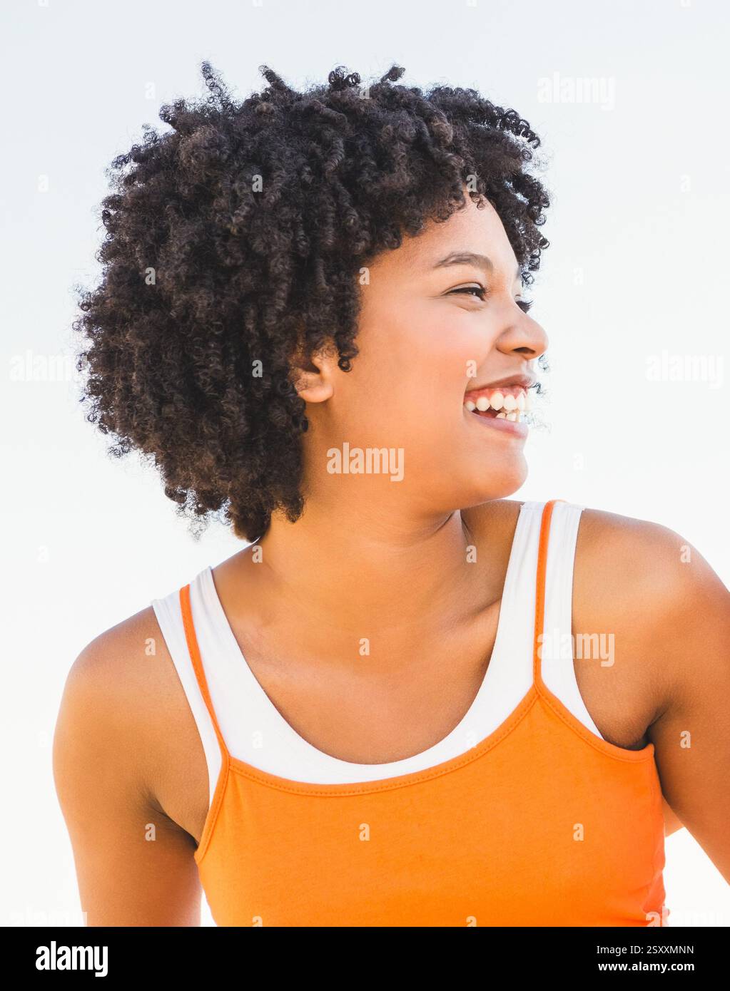 Lächelnde Frau genießt Outdoor-Übungen in leuchtend orangefarbenem Sporttop Stockfoto