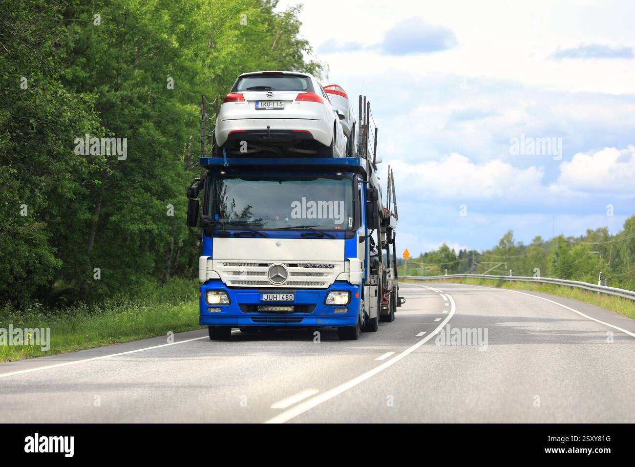 Blauweißer Mercedes-Benz Actros-Autoträger transportiert Fahrzeuge auf der Straße, Vorderansicht. Salo, Finnland. Juni 2024. Stockfoto