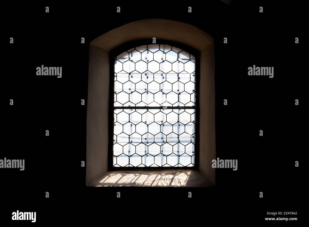 Historisches Ambiente: Klassisches Fenster mit Buntglas in einem alten Gebäude. Sonnenlicht strömt durch das gemusterte Glas Stockfoto