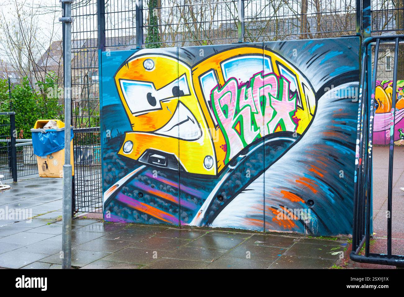 Graffiti-Kunstwerk eines gelb gemeinen Zuges auf dem Gitter eines kleinen Fußballspielplatzes im Stadtteil Zuidplas, Waddinxveen, Niederlande Stockfoto