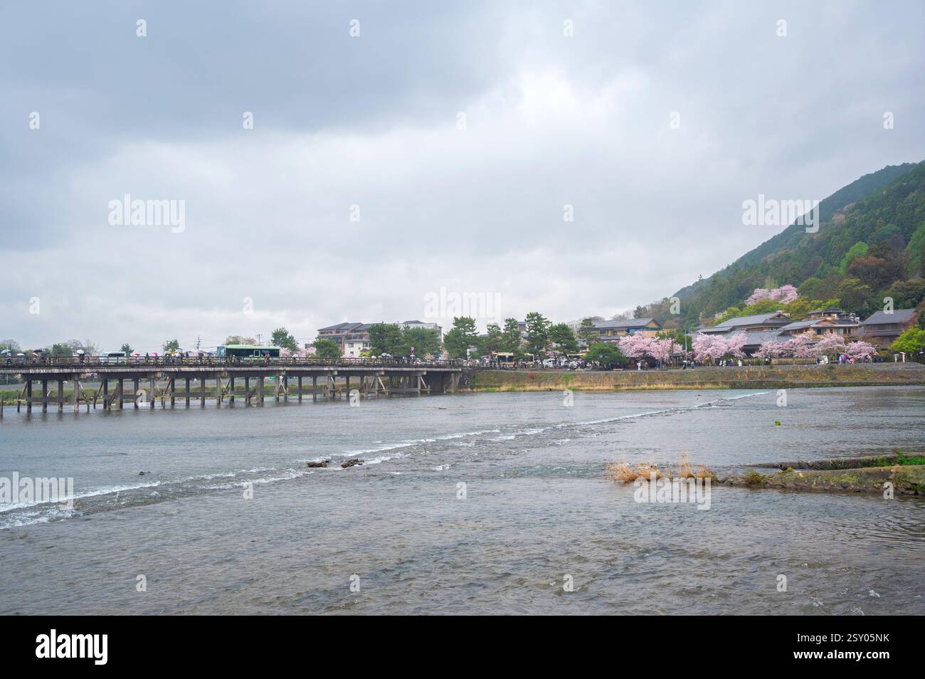 Touristen an der Togetsu-kyo-Brücke, einer Holzbrücke, die den Katsura-Fluss vor den Arashiyama-Bergen in Kyoto, Japan überspannt. Stockfoto