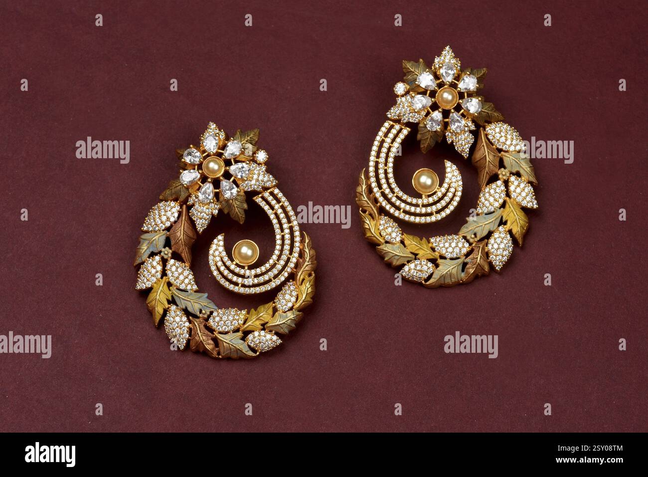 Glamouröses antikes goldenes Paar Ohrringe auf rotem Hintergrund. Luxuriöser Damenschmuck, traditioneller indischer Schmuck, Kundan-Ohrringe, Bridal Gold-Ohrringe Stockfoto