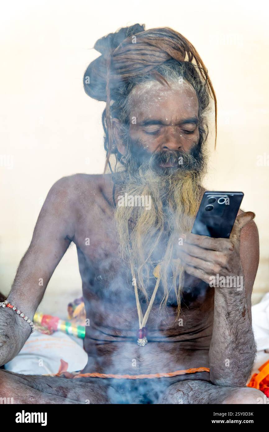 Spirituelle hindu Naga heilige schaut Handy in Mahakumbh Mela Stockfoto