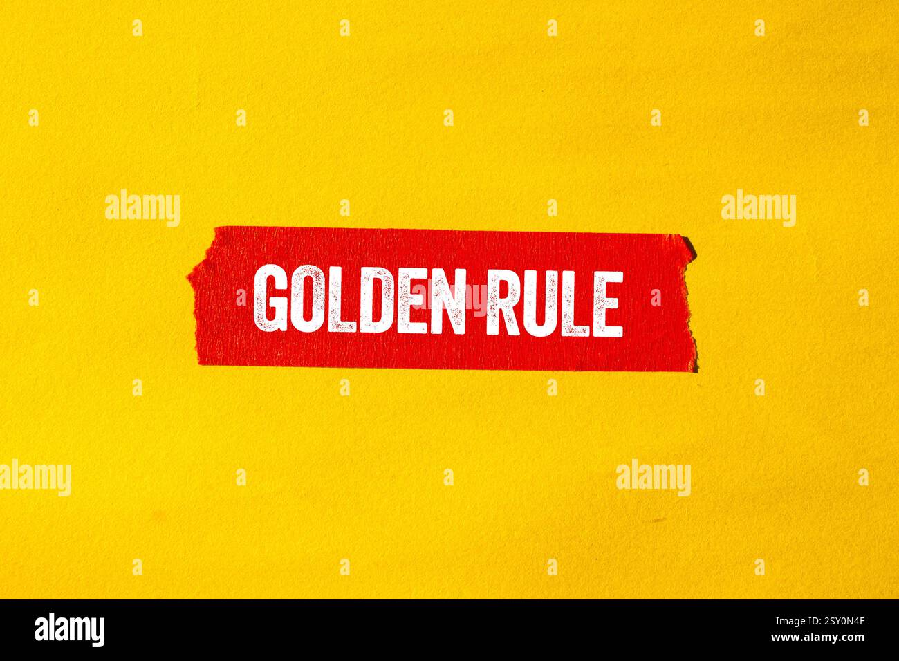 Goldene Regelnachricht auf gerissenem rotem Papierband auf gelbem Hintergrund. Konzeptionelles goldenes Regelsymbol. Kopierbereich. Stockfoto