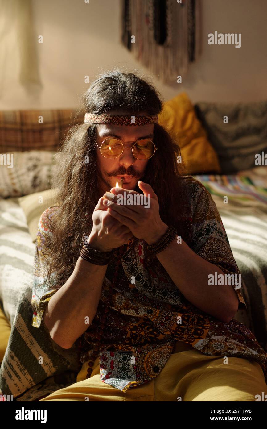 Meditierender Mann in bunter Kleidung, der auf dem Sofa sitzt Stockfoto