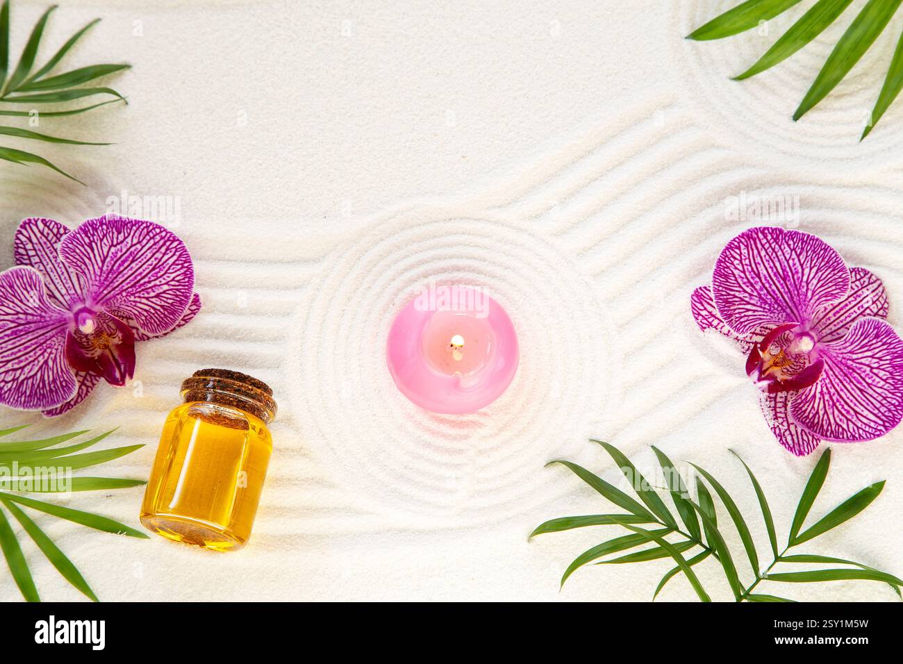 Aromatisches Öl, brennende Kerze und eine Orchidee auf Sandgrund Stockfoto