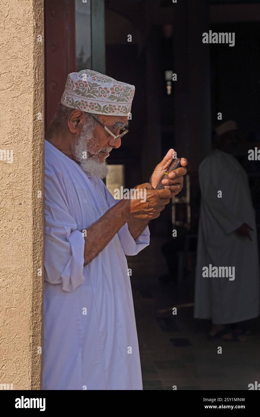Omani man schreibt auf Handy am Nizwa Market (Souk) Oman Stockfoto