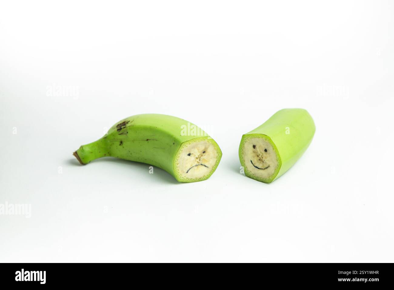 Ein Strang grüner Bananen ist auf weißem Hintergrund gestapelt und zeigt eine Nahaufnahme der unreifen Früchte Stockfoto
