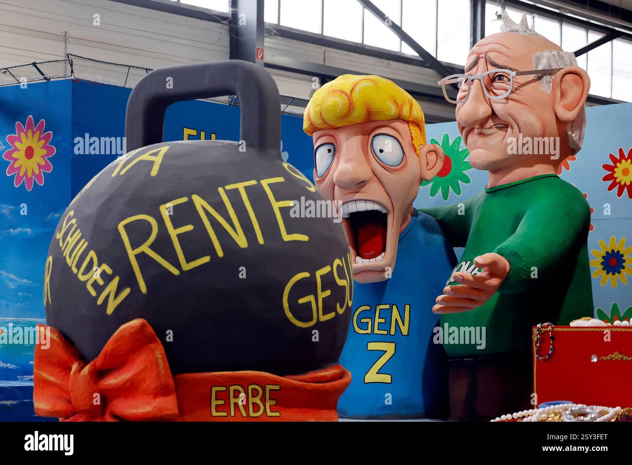 Ein Motivwagen mit dem Thema Generationenkonflikt zeigt einen Boomer, der einem Vertreter der Generation Z einen Schuldenberg aus Rente und Gesungheitskosten hinterlässt, eingewickelt in eine Schlaufe mit der Aufschrift Erbe, zu sehen beim Richtfest für die Wagen des Kölner Rosenmontagszug 2025 im Kölner Karnevalsmuseum. Köln, 25.02.2025 NRW Deutschland *** Ein Auftrieb zum Thema Generationskonflikt zeigt einen Boomer, der einem Vertreter der Generation Z einen Berg Schulden aus Renten- und Gesundheitskosten hinterlässt, umwickelt in einer Schleife mit der Inschrift Erbe, die bei der Richtfeier zu sehen ist Stockfoto