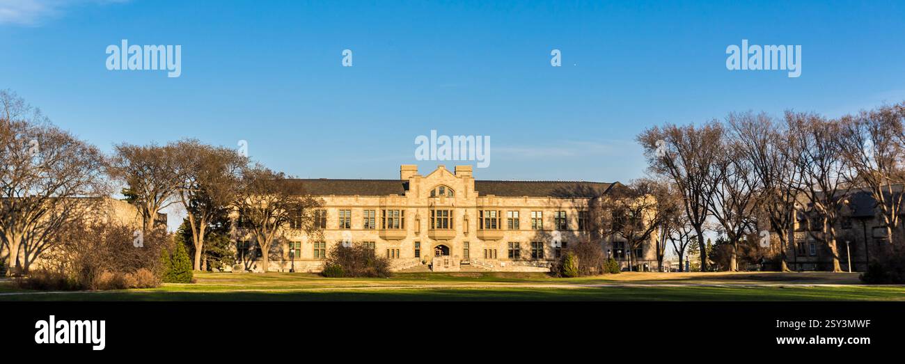 Großes Gebäude mit vielen Fenstern. Das Gebäude ist von Bäumen umgeben. Der Himmel ist blau und klar Stockfoto