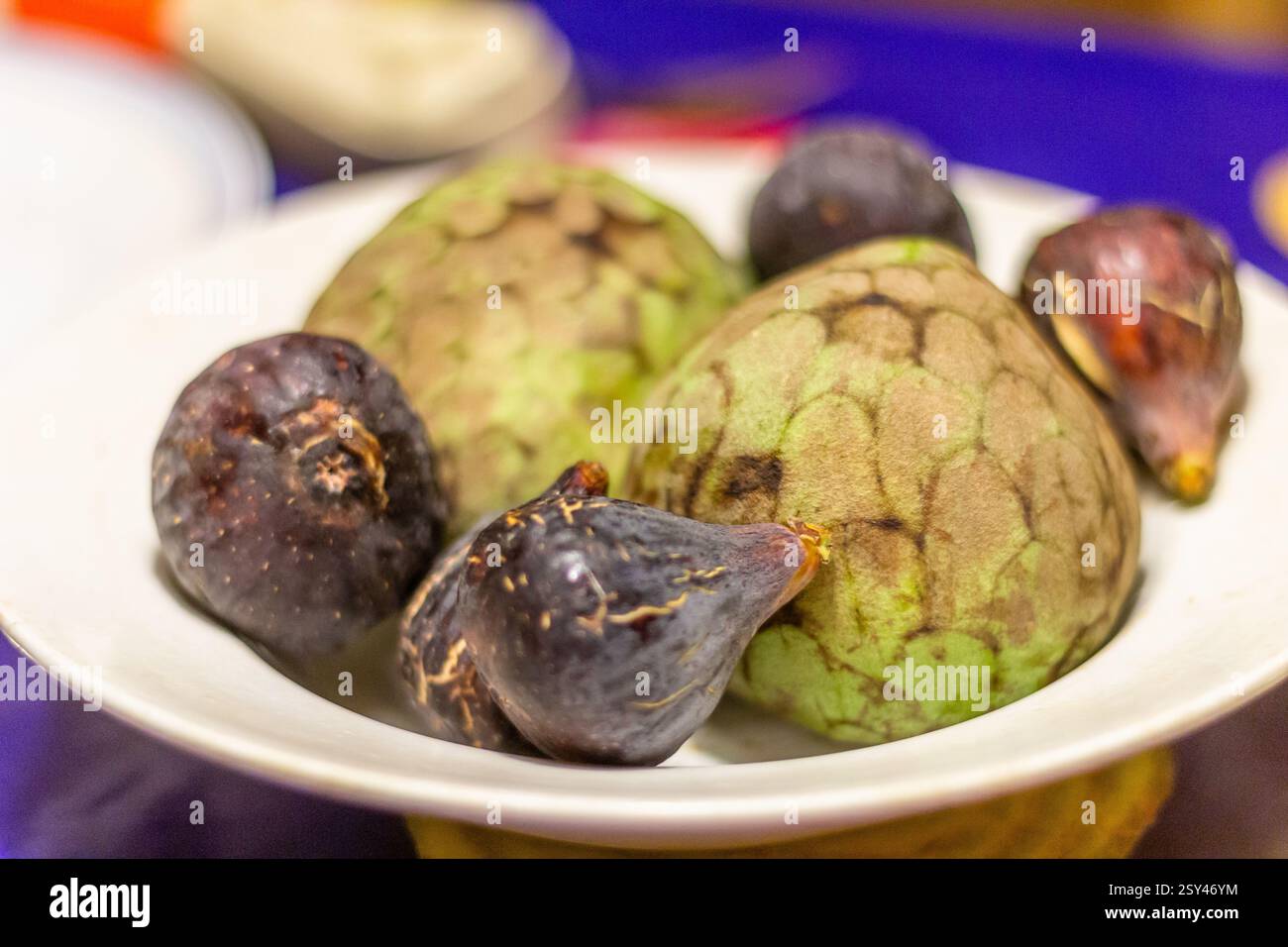 Ein Teller mit frischen Feigen und Cherimoya, serviert in Terrassa, Spanien, eine süße und saisonale Fruchtkombination, die in mediterranen Häusern beliebt ist Stockfoto