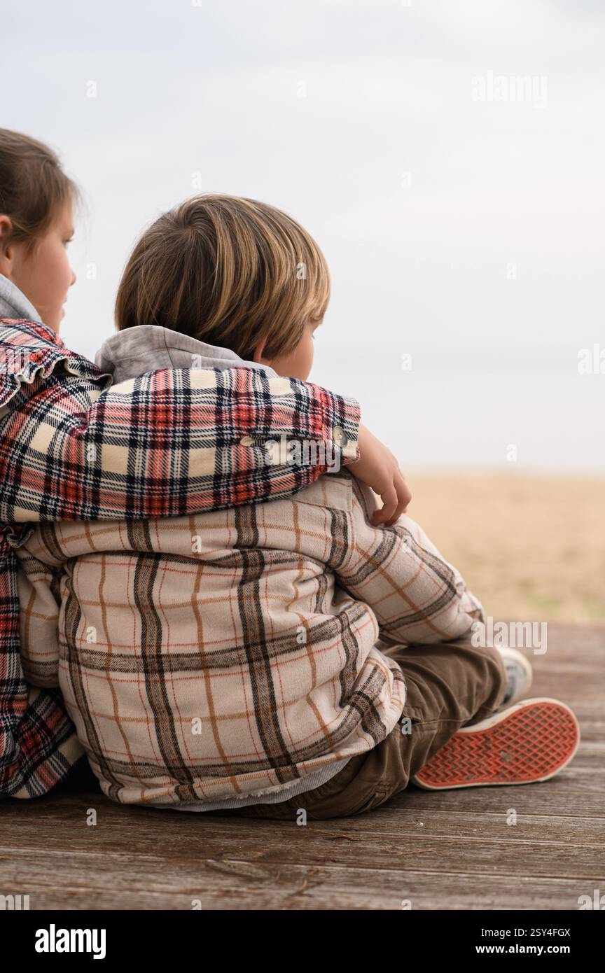 Bruder und Schwester umarmen sich am Strand nahe am Meer Stockfoto