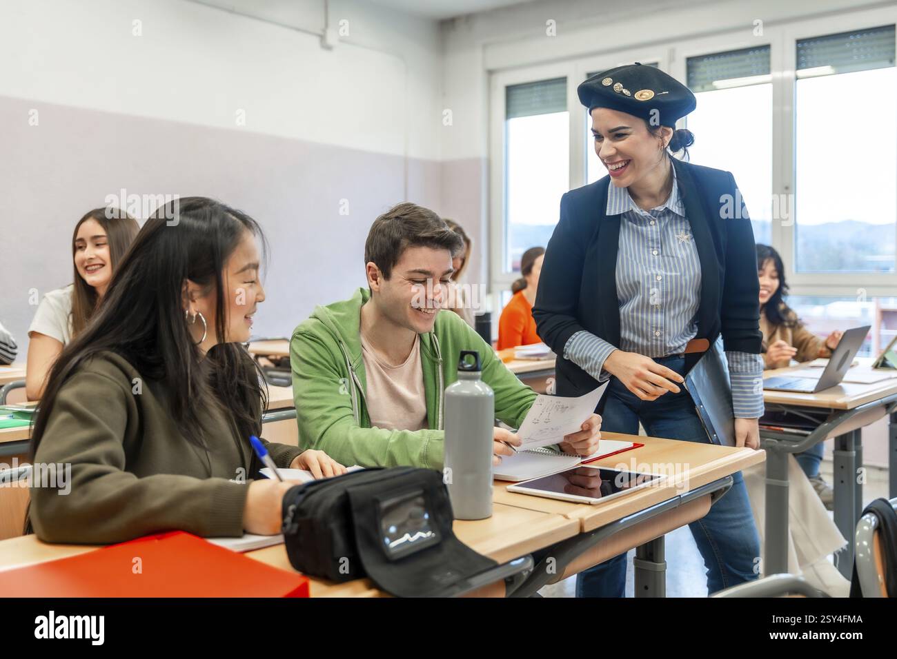 Glücklicher Lehrer, der Studenten beim Lernen und bei der Vorbereitung der Prüfung im Universitätsklassenzimmer hilft Stockfoto