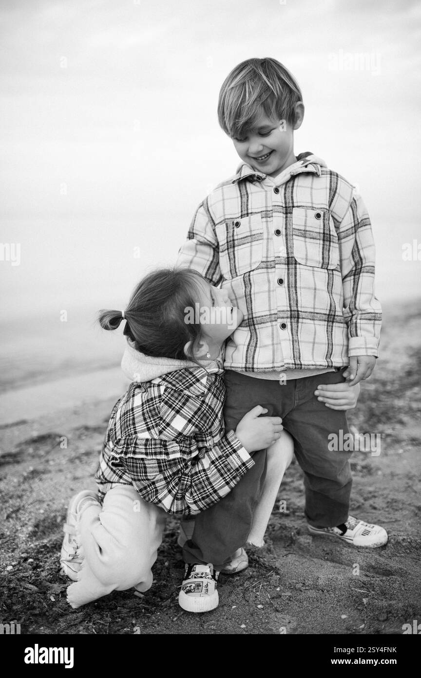 Bruder und Schwester umarmen sich am Strand nahe am Meer Stockfoto